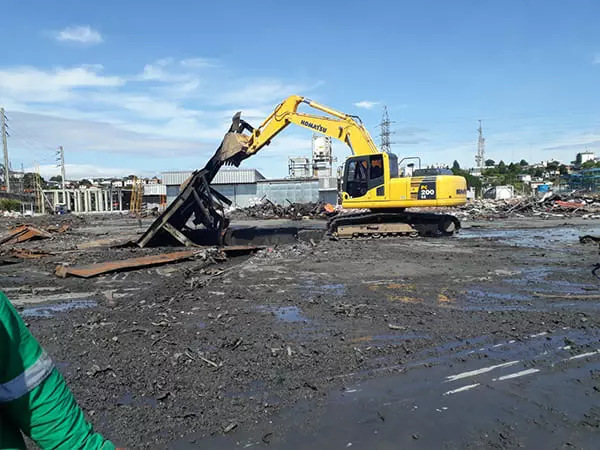 Empresa demolidora J.E.S Demolidora realizando demolição industrial com escavadeira